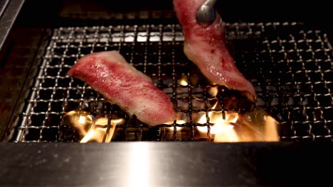 steak slices cooking on a flaming grill