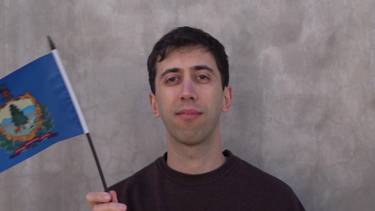 Caucasian person waving Vermont flag in slow motion. America state flag concept.