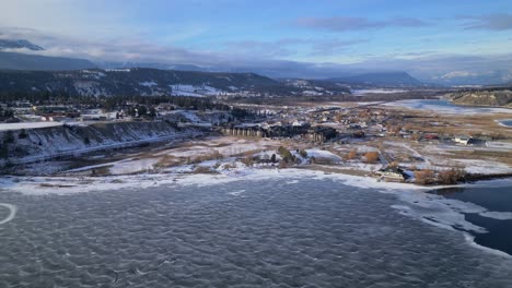 Aerial-drone-view-of-Windermere-Lake-frozen-over-passing-overhead-of-the-city-of-Windermere