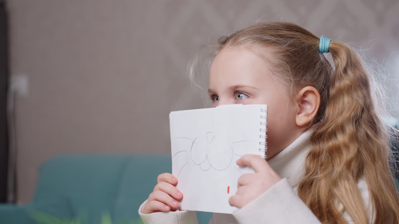 Young girl with long hair in ponytail wearing white turtleneck sitting indoors on sofa with closed eyes and calm expression, appearing thoughtful, relaxed, meditative, enjoying peaceful moment