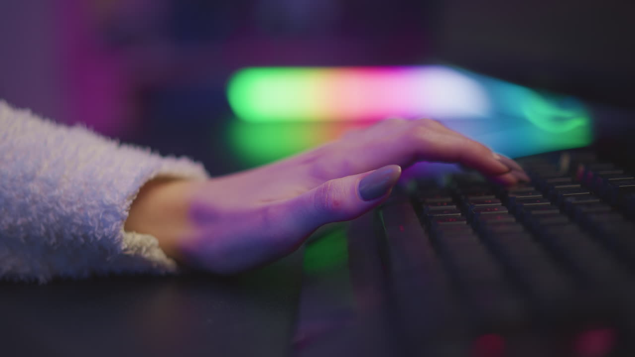 side view of girl hand in fluffy teddy bear sweater typing on illuminated mechanical keyboard with vibrant rgb glow lighting, showcasing polished nails and focused gaming atmosphere in dim ambient