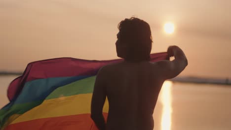 Silhouette of a Man with Rainbow Flag at Sunset