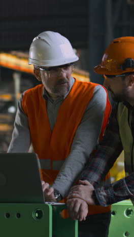 factory workers discussing project at laptop