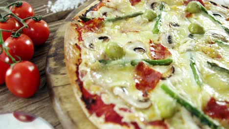 italian pizza on wooden table with vegetables and spices