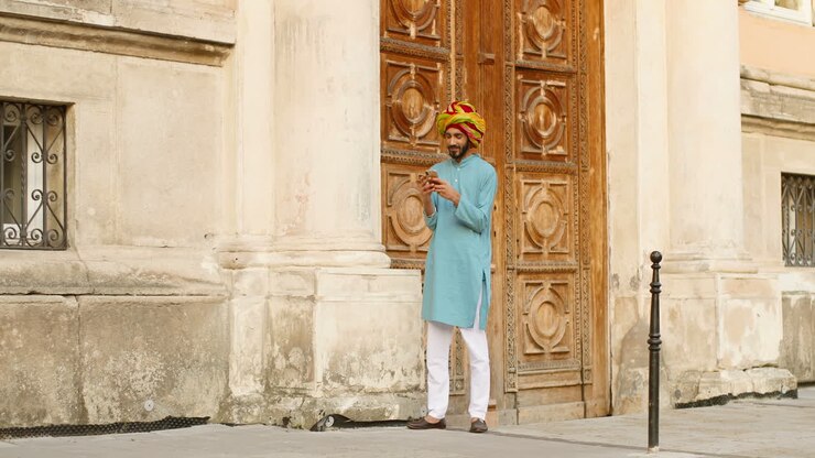 Bel homme indien portant un turban et lisant quelque chose sur son smartphone