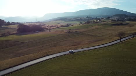 Wunderschöne-Landschaft-Bei-Sonnenuntergang-Mit-Bergen-Und-Einem-Auto-Auf-Einer-Einsamen-Straße