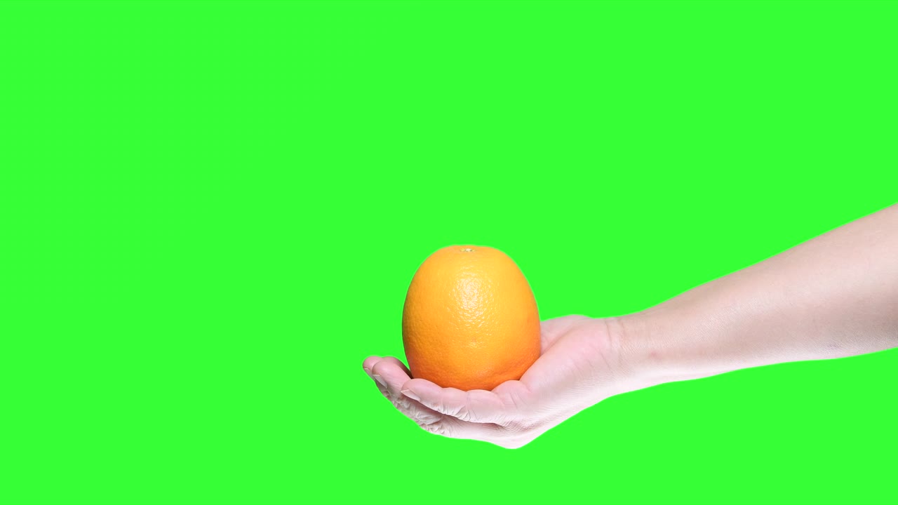 mano sosteniendo naranja aislado en el fondo de la pantalla verde