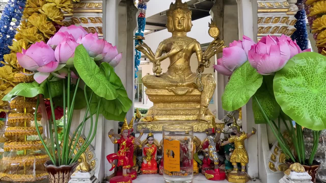 Close-up of a golden statue surrounded by colorful garlands and lotus flowers.