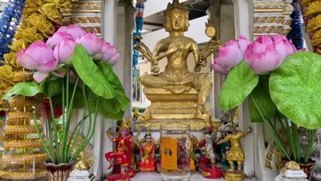 close-up of a golden statue surrounded by colorful garlands and lotus flowers.