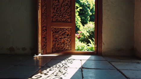 ornately carved wooden door opening to a garden