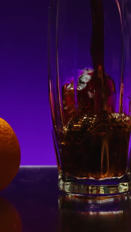 pouring drink into a glass with orange