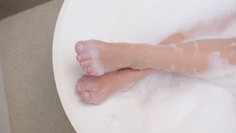 relaxing in bathtub, woman enjoying bubble bath with feet submerged in water