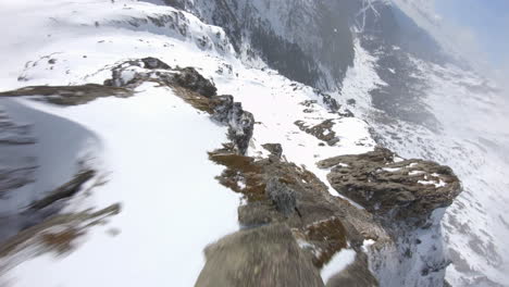 Freestyle-flight-of-racing-drone-flying-over-snowy-mountainous-landscape-of-Pyrenees-mountain-range