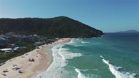 a lateral aerial image reveals praia brava with several paragliders soaring in the background