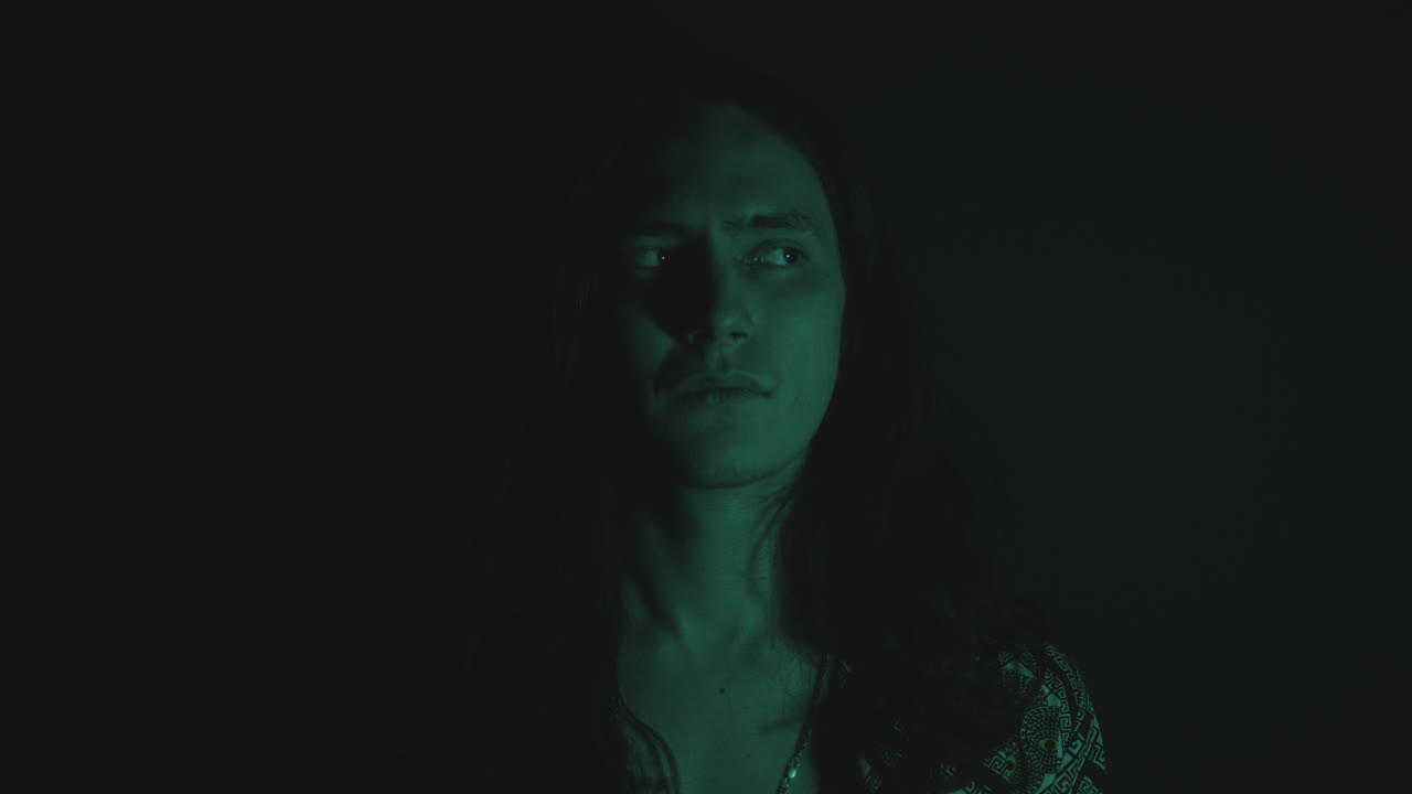 Young Man Looking at Side as Posing in Dark Studio with Blinking Light