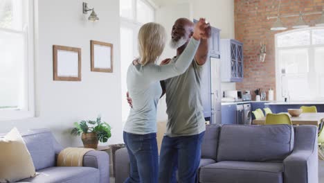 pareja de alto nivel de raza mixta bailando juntos en la sala de estar en casa