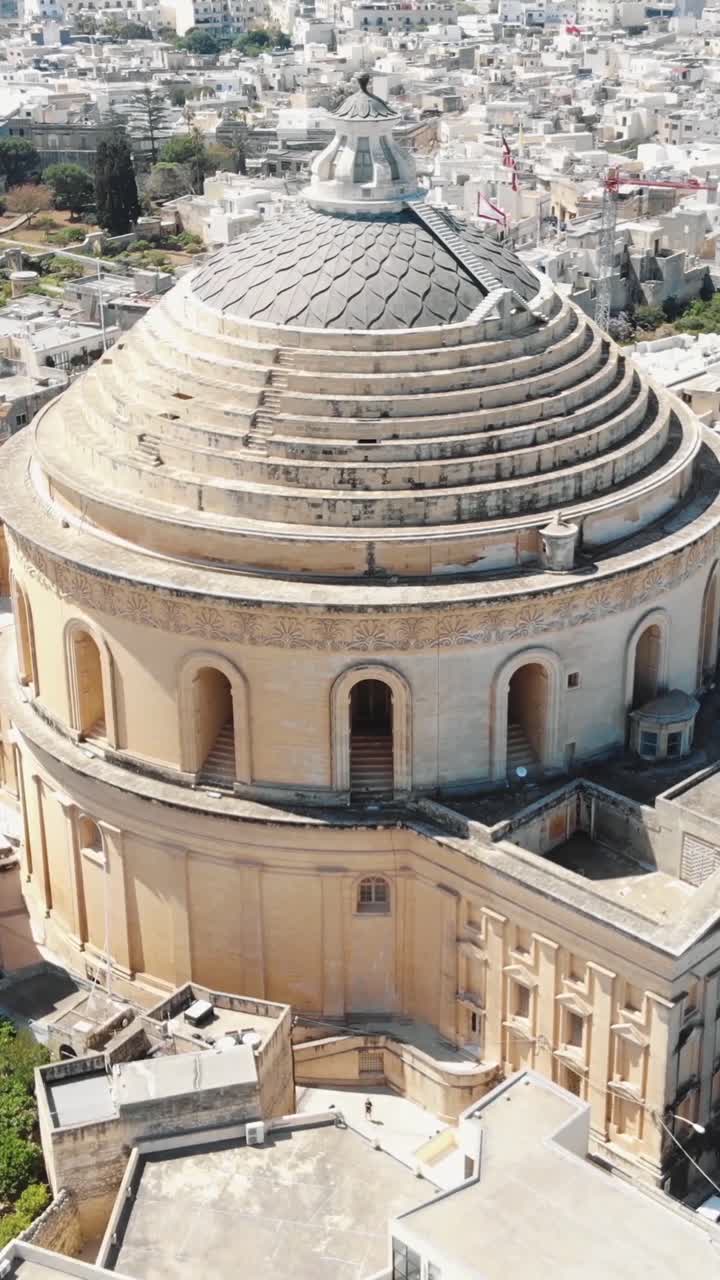 Scenic aerial view showcasing the architectural beauty of Mosta Rotunda in Malta. Vertical video, circle dolly