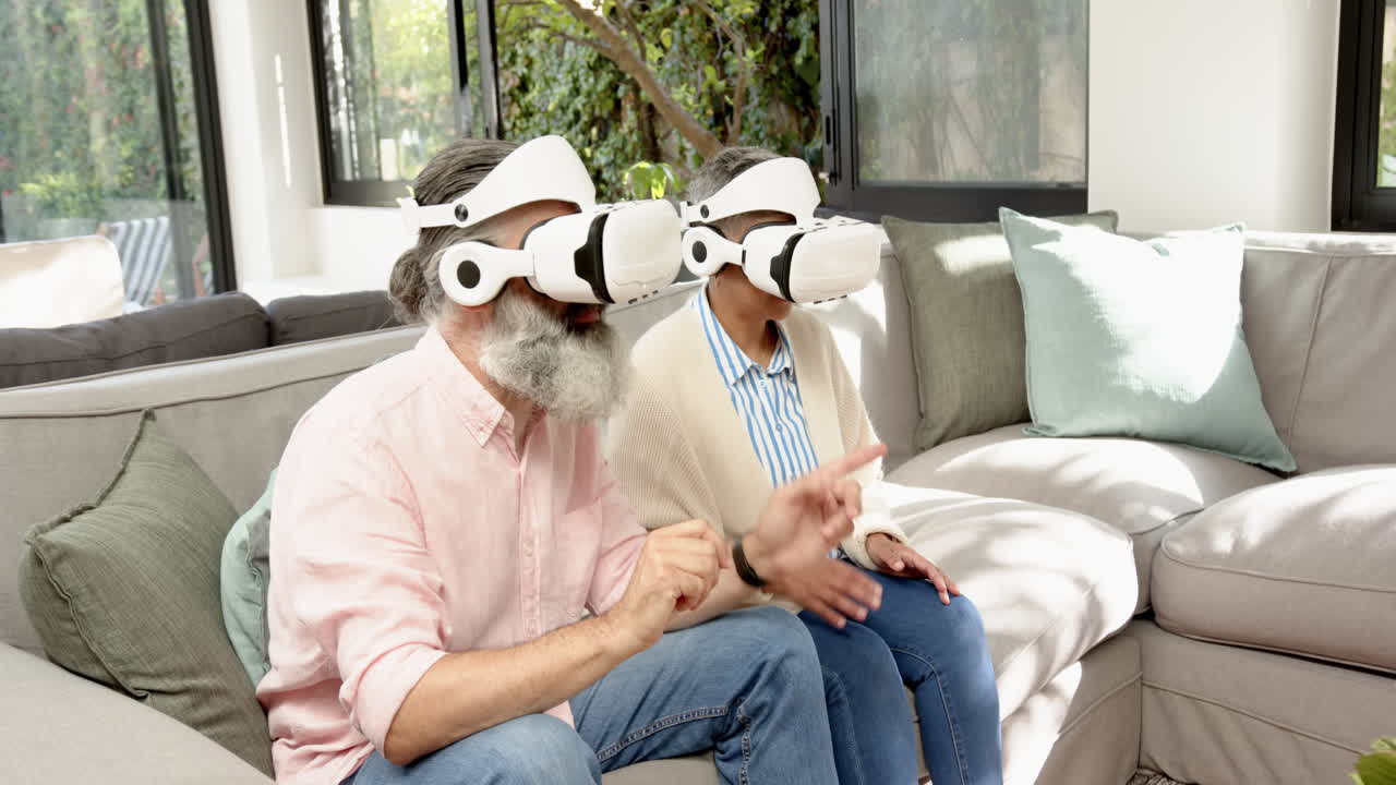 Using VR headsets, senior couple enjoying virtual reality experience on sofa