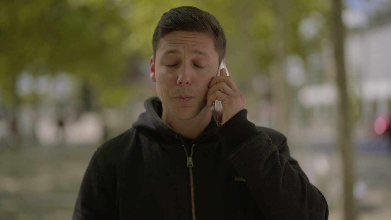 밖에서 스마트 폰으로 이야기하는 행복한 젊은 남자