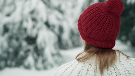 caucasian woman wearing red hat walking in snowing forest