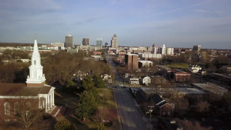 aerial shot flying toward greensboro north carolina skyline with first baptist church of greensboro in the foreground