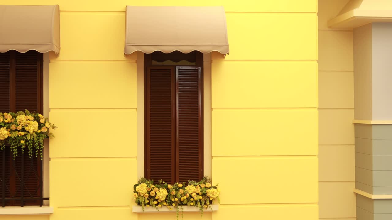 edificio amarillo con persianas marrones y flores