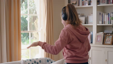 cool teenage girl dancing wearing headphones listening to music having fun teenager celebrating with crazy dance moves at home enjoying freedom on weekend 4k