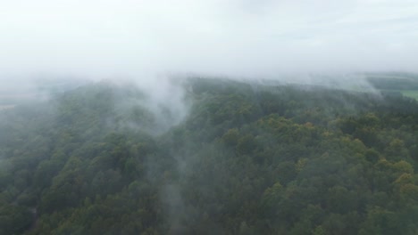 Aerial-view-of-a-hilly-landscape-of-forests-shrouded-in-fog