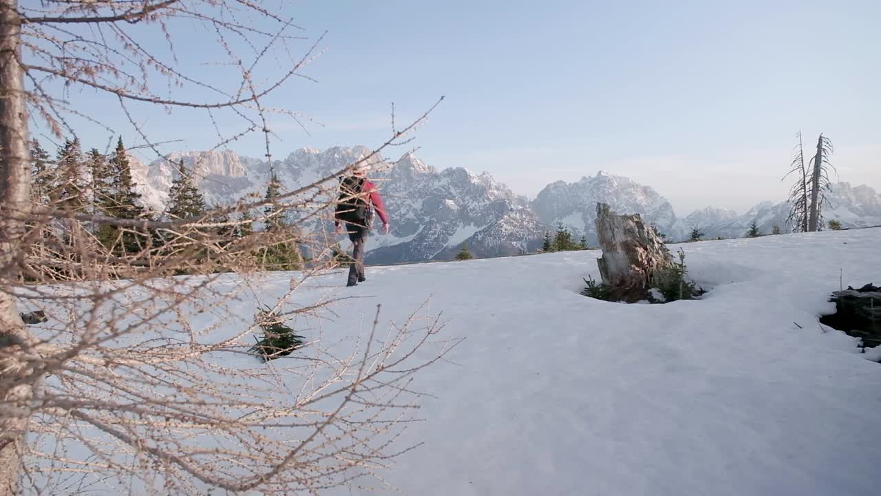 excursionista alejándose de la cámara hacia los alpes julianos con el suelo cubierto de nieve