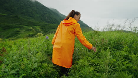 woman hiking in mountains with orange raincoat