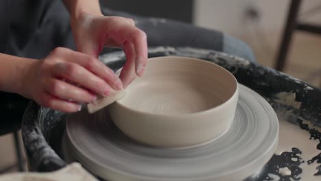 hands of a master potter working on a potter's wheel, forming a bowl of clay. close-up, slow motion