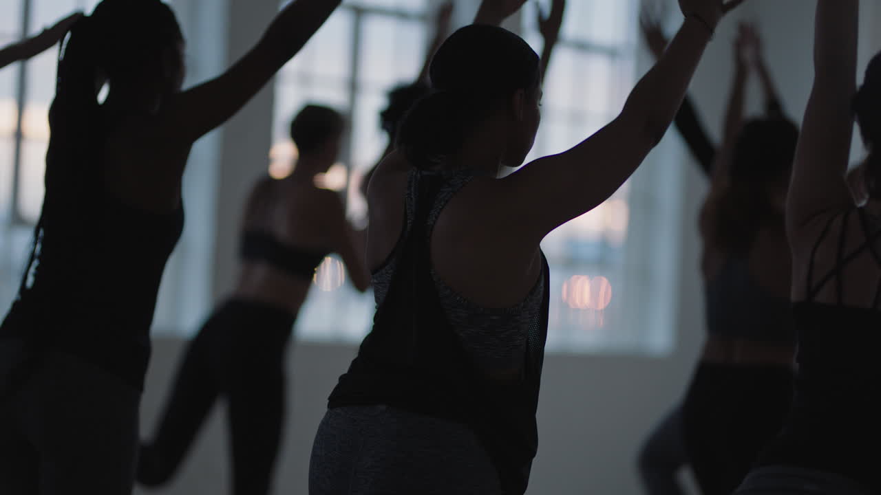 gruppo di lezioni di yoga di donne multirazziali che praticano la posa del guerriero godendo di uno stile di vita sano che si esercita nella sala fitness all'alba