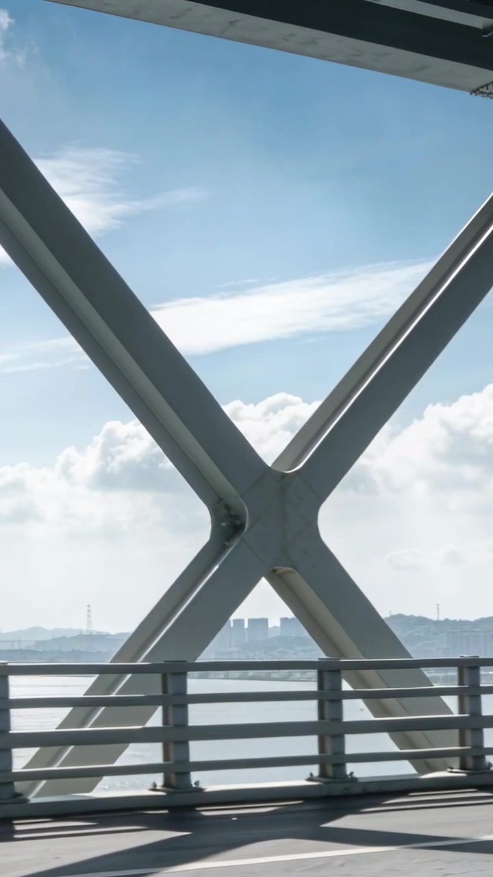 Video verticale: Telecamera panoramica che si muove a destra lungo un ponte a traliccio, rivelando un guardrail, l'acqua e l'orizzonte.