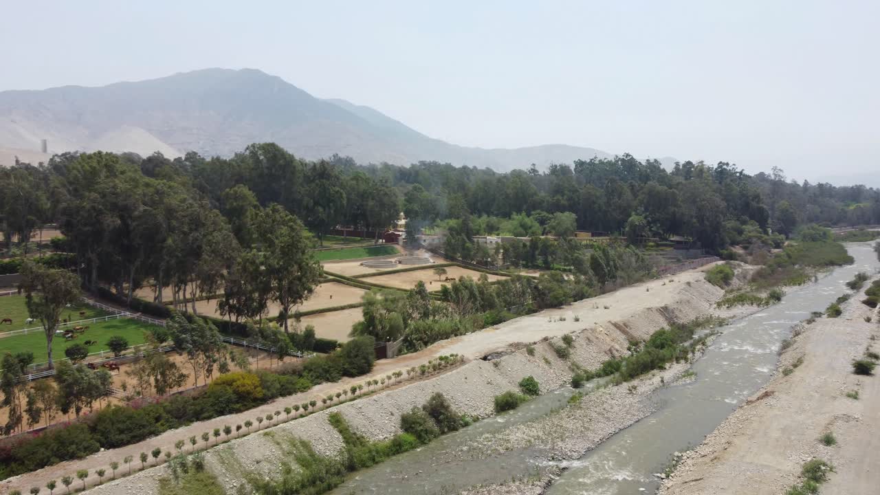 dron en órbita sobre un pequeño río rodeado por una zona boscosa con algunas pequeñas parcelas de tierra