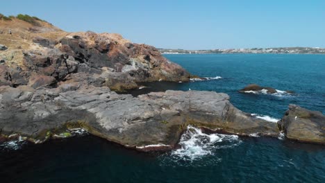 Aerial-shot-of-big-rocks-in-the-sea-and-seagulls-landed,-sunny-summer-day