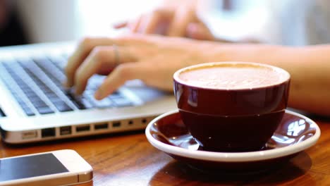 mujer de negocios usando una computadora portátil con una taza de café en la mesa