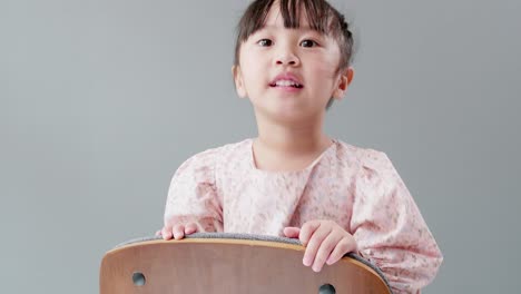 Child-playing-on-the-chair-at-home-and-looking-at-camera