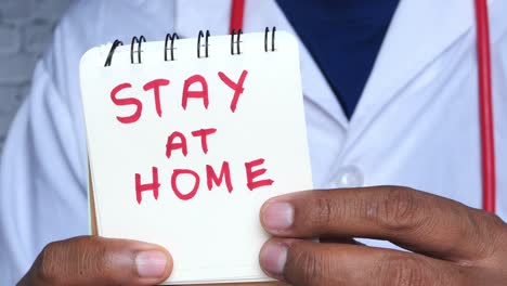 doctor holding a note that says "stay at home".