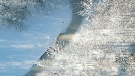 low winter sun casting long horizontal shadow lines on beautiful frozen river and snow landscape in finland, top down aerial