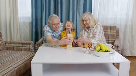 grandparents and granddaughter playing a tower game