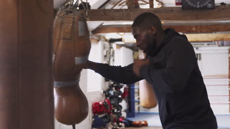 male boxer in gym training with old fashioned punch bag