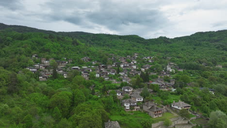 aerial view of kovachevitsa in bulgaria - hillside village with traditional stone houses surrounded by lush mountain scenery.
