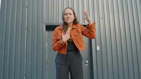 furious woman stands in front of closed door, moving hands vigorously in air