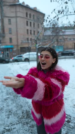 mujer con abrigo de piel falsa rosa disfrutando de la nieve