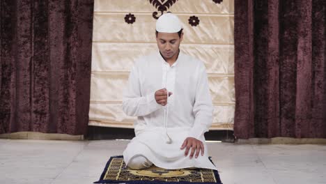 indian muslim man praying to allah using beads