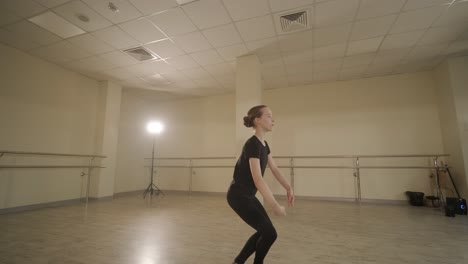 un grupo de jóvenes estudiantes de ballet con ropa de baile negra practicando posiciones en un amplio estudio de ballet con pisos de madera y barras montadas en la pared. expresiones enfocadas y movimientos sincronizados.