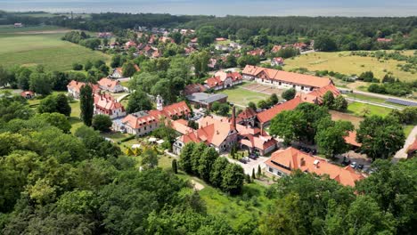 drone flight over the buildings of the old manor in kadyny, view of buildings, trees, and a bay