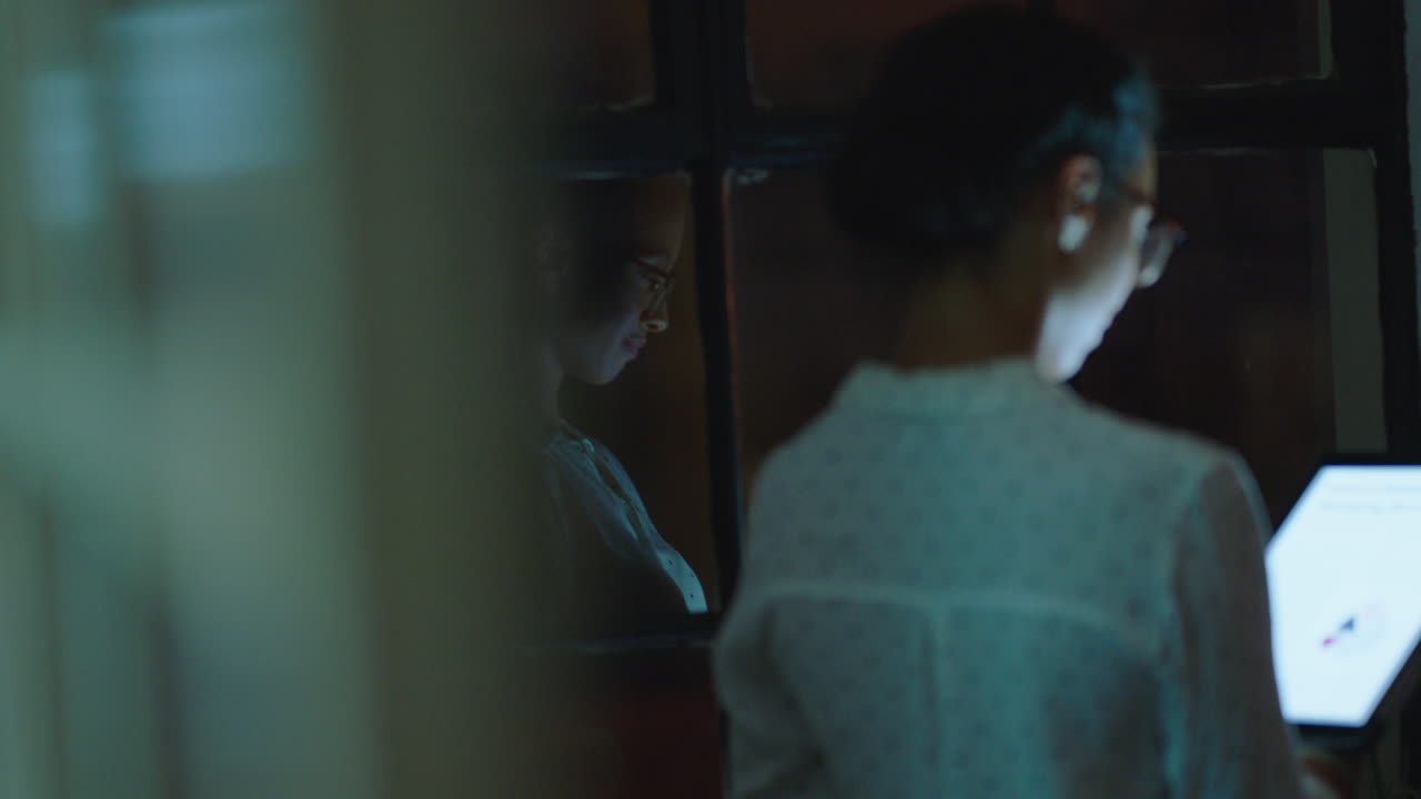 아름다운 비즈니스 여자가 태블릿 컴퓨터를 사용하여 늦게 일하고 스크린에서 연구 데이터 통계를 탐색하고 성공적인 프로젝트 마감기간 전략을 바라보고 창문을 내다보고 앞으로 계획합니다.