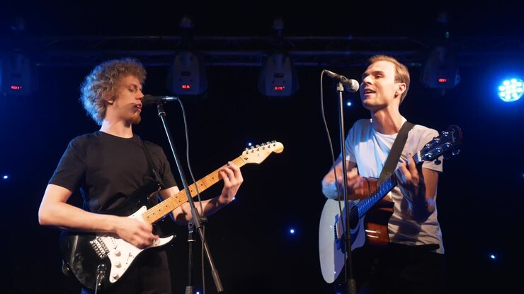 Concerto di una rock band che si esibisce sul palco con due chitarristi e cantanti. Video musicale di un gruppo punk, heavy metal o rock. Band di due uomini che suonano strumenti al rallentatore