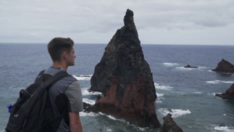 man stands in front of famous rock formation at ponta de sao lourenco